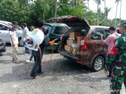Penyemprotan disinfektan terhadap kendaraan di perbatasan Kabupaten Poso dengan Kabupaten Parigi Moutong, Sulawesi Tengah, 26 Maret 2020. (Foto: Humas Pemkab Poso)