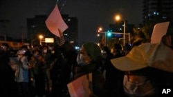 Protesters hold up blank papers and chant slogans as they gather on a street during a protest in Beijing, Nov. 27, 2022.