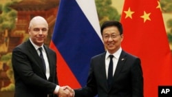 资料照:2019年11月26日,在北京人民大会堂举行的签字仪式前,俄罗斯第一副总理兼财政部长西卢安诺夫(左)与现任中国国家副主席韩正握手。(美联社)