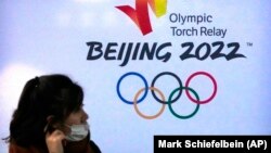 资料照片：一名女性在北京邮电大学内的北京冬奥广告前（2021年12月9日）