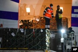 Pekerja membongkar kiriman bantuan militer yang dikirim sebagai bagian dari bantuan keamanan Amerika Serikat ke Ukraina, di bandara Boryspil, di luar Kyiv, Ukraina, 25 Januari 2022. (Foto: AP)