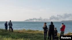 Ljudi gledaju kako gore cisterne za gorivo i oštećuju delove mosta Kerč, Krim, 8. oktobar 2022.(Foto: Rojters)