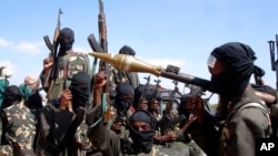 FILE - Armed al-Shabab fighters ride on pickup trucks as they prepare to travel into the city, just outside the capital Mogadishu, in Somalia, Dec. 8, 2008.
