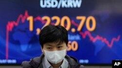 A currency trader walks near the screen showing the foreign exchange rate between U.S. dollar and South Korean won at a foreign exchange dealing room in Seoul, South Korea, Monday, March 7, 2022. (AP Photo/Lee Jin-man)