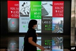 Seorang perempuan berjalan melewati papan elektronik yang memajang harga saham di Bursa Efek Indonesia, Jakarta, Kamis, 7 Oktober 2021. (AP/Dita Alangkara)