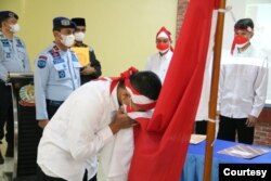 Satu dari delapan narapidana terorisme di Sumut sedang mencium bendera Merah Putih, Rabu 9 Maret 2022. (Courtesy: Humas Kemenkumham Sumut).