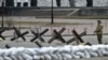 A member of Ukraine's Territorial Defense Forces, the military reserve of Ukraine's Armed Forces, stands guard next to anti-tank barriers blocking a street in Kyiv, March 6, 2022.