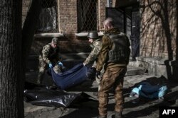 Military emergency service members remove the body of a dead Ukrainian serviceman in the area of a research institute, part of Ukraine's National Academy of Science, after a strike, in northwestern Kyiv, March 22, 2022.