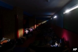 Ljudi se pripremaju za noć u improvizovanom skloništu od bombi u sportskom centru u Marijupolju, u nedelju kasno uveče, 27. februara 2022. (AP Photo/Mstislav Černov)