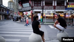 FILE - People rest on stone barricades on a street, following the coronavirus disease (COVID-19) outbreak, in Shanghai, China, Sept. 9, 2022.
