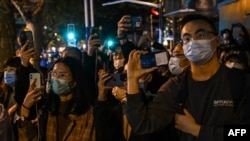 People gather on a street in Shanghai on November 27, 2022, where protests against China's zero-Covid policy took place the night before following a deadly fire in Urumqi, the capital of the Xinjiang region.