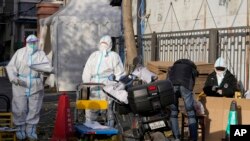 Workers in protective clothing control access into a community under lockdown in Beijing, Friday, Nov. 25, 2022. 