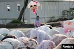 FOTO FILE: Gadis muslimah memegang balon saat mengikuti salat berjamaah Idulfitri di pelabuhan Sunda Kelapa, Jakarta, 2 Mei 2022. (REUTERS/Willy Kurniawan)