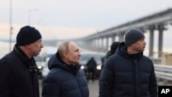 Presiden Rusia Vladimir Putin (tengah) dan sejumlah pejabat pemerintahan Rusia berkunjung ke area Jembatan Krimea yang menghubungkan wilayah daratan Rusia dengan Semenanjung Krimea pada 5 Desember 2022. (Foto: Mikhail Metzel, Sputnik, Kremlin Pool Photo via AP)