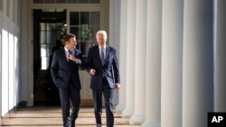 U.S. President Joe Biden and French President Emmanuel Macron walk down the Colonnade to the Oval Office at the White House, Dec. 1, 2022.