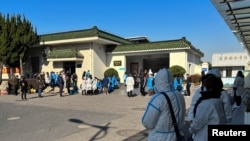 People wearing personal protective equipment (PPE) stand outside a funeral home, as coronavirus disease (COVID-19) outbreak continues, in Shanghai, China December 24, 2022. (Reuters)