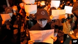 Protesters hold up blank papers and chant slogans as they march in Beijing, Nov. 27, 2022. 