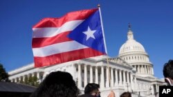 Seorang perempuan tampak mengibarkan bendera Puerto Rico dalam konferensi pers mengenai status Puerto Rico di Gedung Capitol, Washington, pada 2 Maret 2021. (Foto: AP/Patrick Semansky)