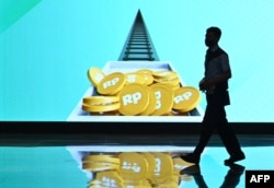 Seorang pria berjalan di samping layar di Bursa Efek Indonesia (BEI) di Jakarta, 2 Januari 2023. (ADEK BERRY/AFP)