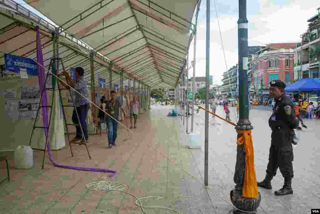 មន្ត្រីប៉ូលិសម្នាក់ឈរល្បាត ខណៈមន្ត្រីរៀបចំការបោះឆ្នោតកំពុងរៀបចំមណ្ឌលបោះឆ្នោតមួយកន្លែង មួយថ្ងៃមុនការបោះឆ្នោតឃុំសង្កាត់អាណត្តិទី ៥ ក្នុងសង្កាត់ផ្សារកណ្តាលទី ២ ខណ្ឌដូនពេញ ភ្នំពេញ ថ្ងៃសៅរ៍ ទី ៤ ខែមិថុនា ឆ្នាំ ២០២២។ (ខាន់ សុគុំមនោ/វីអូអេ)