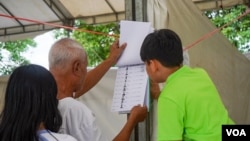 រូបឯកសារ៖ បុរសម្នាក់ផ្ទៀងផ្ទាត់ឈ្មោះនៅក្នុងបញ្ជីឈ្មោះអ្នកបោះឆ្នោត មួយថ្ងៃមុនថ្ងៃបោះឆ្នោតឃុំសង្កាត់អាណត្តិទី ៥ នៅសង្កាត់ផ្សារកណ្តាលទី ១ ខណ្ឌដូនពេញ រាជធានីភ្នំពេញ ថ្ងៃសៅរ៍ ទី ៤ ខែមិថុនា ឆ្នាំ ២០២២។ (ខាន់ សុគុំមនោ/វីអូអេ)