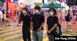 周嘉发(左一)与该党主席陈宝莹(右一)及成员余炜彬，6月4日晚在铜锣湾进行默站快闪悼念六四行动 (社民连社交网站图片)