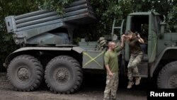在乌南尼古拉耶夫地区的前线附近，一名乌克兰女军人在丈夫兼战友的帮助下跳下BM21“冰雹”多管火箭发射车。(2022年9月16日)