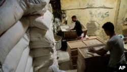 Workers prepare to bake Egyptian traditional 'Baladi' flatbread, beside wheat sacks inside a bakery, in the Old Cairo district of Cairo, Sept. 8, 2022.