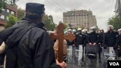 Protivnik Evroprajda nosi krst ispred kordona koji mu sprečava prolaz, u Takovskoj ulici u Beogradu, 17. septembra 2022. (Foto: VOA/Jovana Đurović)