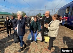 Nataliia Yelistratova with her husband Mykhailio and daughter Olena Miroshnychenko stand at a platform of a railway station after arrival to their hometown of Balakliia, which was recently liberated by the Ukrainian armed forces
