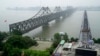 FILE - Visitors cross the Yalu River Broken Bridge, right, next to the Friendship Bridge connecting China and North Korea in Dandong China, Sept. 9, 2017. Despite an economic slowdown, China is expected to continue assisting North Korea.