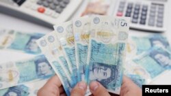 FILE - Woman holds British pound banknotes in this illustration taken May 30, 2022. (Reuters/Dado Ruvic/Illustration)