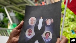 Seorang warga Myanmar yang tinggal di Thailand memegang foto-foto tahanan politik yang dieksekusi di Myanmar, saat berlangsungnya aksi protes di luar kedutaan Myanmar di Bangkok, Thailand, Selasa, 26 Juli 2022.(AP /Sakchai Lalit)