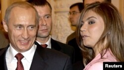 Presiden Rusia Vladimir Putin tersenyum saat melihat ke arah pesenam Rusia Alina Kabaeva dalam pertemuan dengan tim Olimpiade Rusia di Kremlin, Moskow, 4 November 2004. (Foto: Reuters/ITAR-TASS/Presidential Press Service)