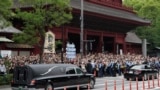 日本前首相安倍晋三的葬礼举行后，运载安倍棺木的灵车离开寺庙，日本民众路旁送行。（2022年7月12日）