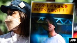 Seorang aktivis memegang foto warga negara Jepang Toru Kubota, yang ditahan di Myanmar, di depan Kementerian Luar Negeri di Tokyo. (Foto: AFP)