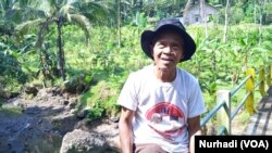 Sodin, di depan ladang yang harus dilepas karena lahan sekitarnya sudah dibeli pemerintah.foto Nurhadi