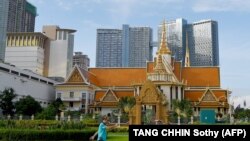 Seorang pria berolahraga di depan gedung Institut Buddhis, yang terletak di sebelah bangunan komersial modern, di Phnom Penh pada 29 Juni 2020. (Foto: AFP/TANG CHHIN Sothy)
