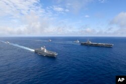 Kapal induk bertenaga nuklir AS USS Ronald Reagan, kanan, dan kapal helikopter platform pendaratan (LPH) Korea Selatan (LPH) Marado, kedua dari kiri, berlayar selama latihan militer bersama di lokasi yang dirahasiakan, Sabtu, 4 Juni 2022. (Foto: via AP)
