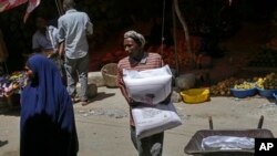 FILE - A man carries a sack of imported wheat flour in the Hamar-Weyne market in Mogadishu, Somalia, May 26, 2022. Families across Africa are paying about more for wheat flour as Russia's war in Ukraine blocks exports from the Black Sea.