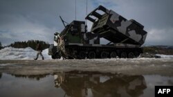 资料照片：在挪威举行的一次国际军演期间，一名军人走过一部M270多管火箭发射系统。(2022年3月22日)