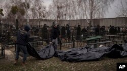 Workers carry the body of people found dead to a cemetery in Bucha, outskirts of Kyiv, Ukraine, April 5, 2022.