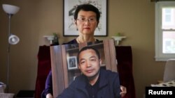 Sophie Luo Shengchun, the wife of jailed Chinese human rights lawyer, Ding Jiaxi, poses with a photo of him at her home in Alfred, New York, July 28, 2022.