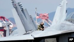 Tentara AS memeriksa jet tempur F/A-18 Super Hornet di dek kapal induk bertenaga nuklir USS Ronald Reagan di Busan, Korea Selatan, 23 September 2022. (Foto: AP)