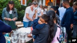 A woman, who is part of a group of immigrants that had just arrived holds a child as they are fed outside St. Andrews Episcopal Church, Sept. 14, 2022, in Edgartown, Mass., on Martha's Vineyard.