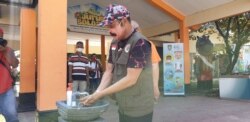 Wali Kota Solo Hadi Rudyatmo ( bermasker fan bertopi), mencuci tangan, dipindai suhu tubuh, disemprot telapak tangan sebelum masuk kompleks Solo Zoo, Jumat, 12 Juni 2020, sebagai simulasi aturan pengunjung/ wisatawan. (Foto: Yudha Satriawan/VOA)