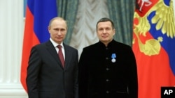 На фото поруч з президентом Росії Володимиром Путіним – один з провідних російських пропагандистів, Володимир Соловйов. Обидва стверджють, що метою війни проти України є «денацифікація» українців, що історик Тімоті Снайдер, вважає «геноцидною риторикою».