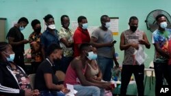 资料照片：在德克萨斯州德尔里奥的一个暂托中心，非法越过美墨边境并自首的移民获得援助。（2021年6月16日）