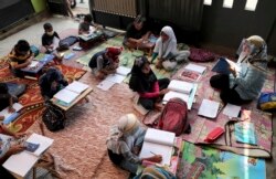 Inggit Andini (kanan) mengenakan masker wajah untuk mencegah penularan virus corona, mengajar murid-muridnya di rumahnya yang dijadikan kelas darurat, di Tangerang, 10 Agustus 2020. (Foto: AP)