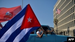 FILE - Cubans drive past the US Embassy during a rally calling for the end of the US blockade against Cuba, in Havana, March 28, 2021.